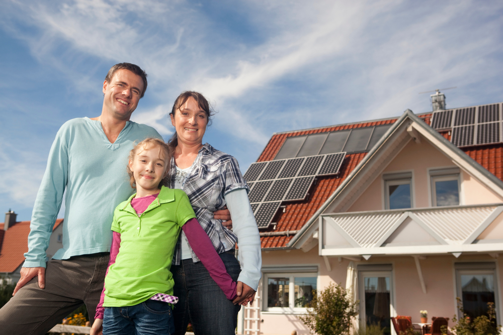 Kleinfamilie vor einem Haus mit Solaranlage