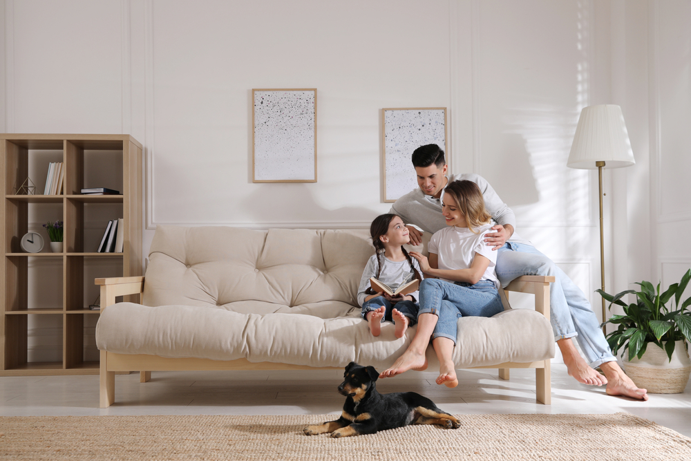 Fröhliche Familie auf Sofa und Welpen im Wohnzimmer