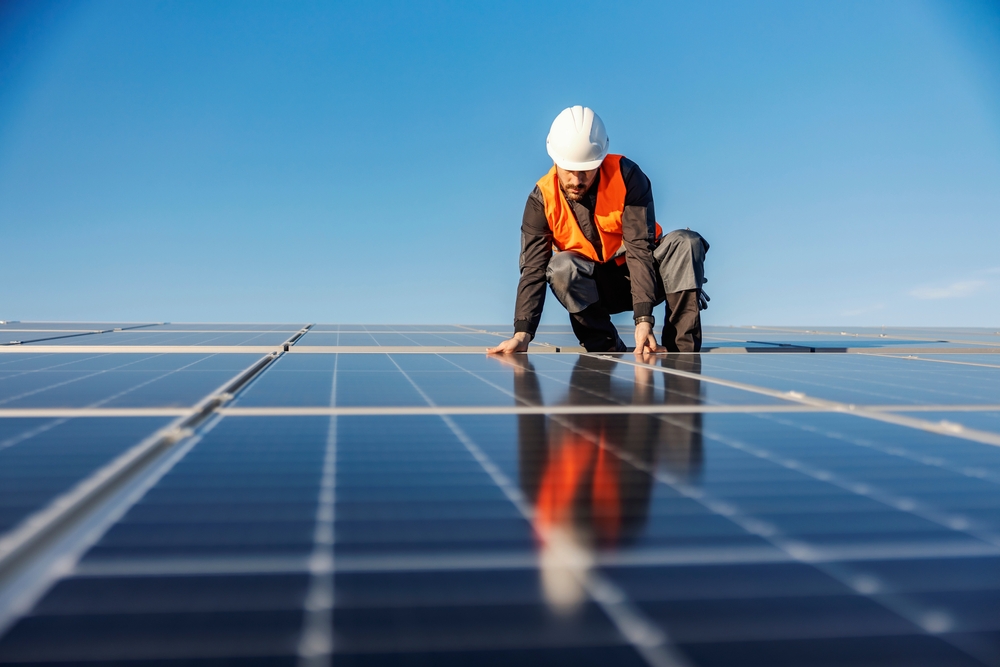 Ein Arbeiter auf dem Dach der die Solaranlage befestigt