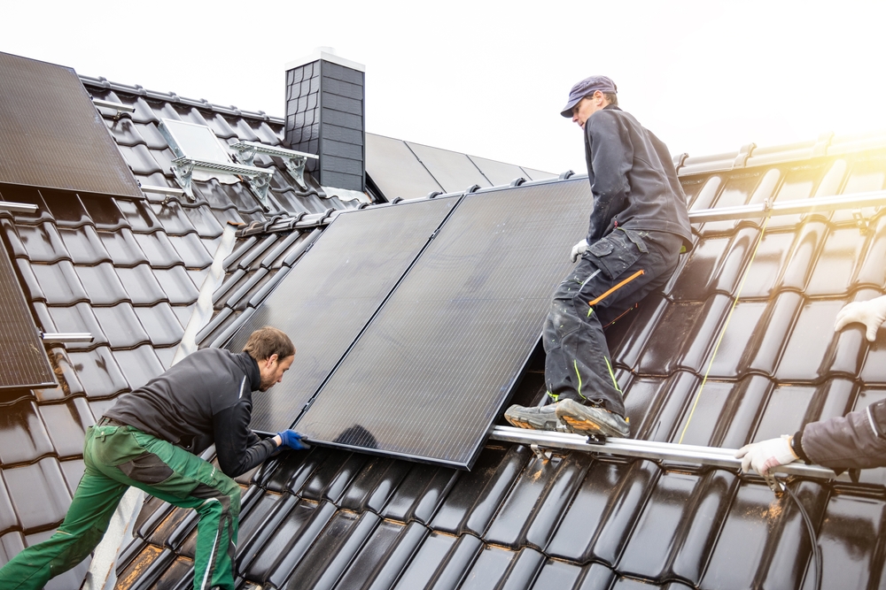 Händler, die Solarpaneele auf dem Dach eines Hauses installieren